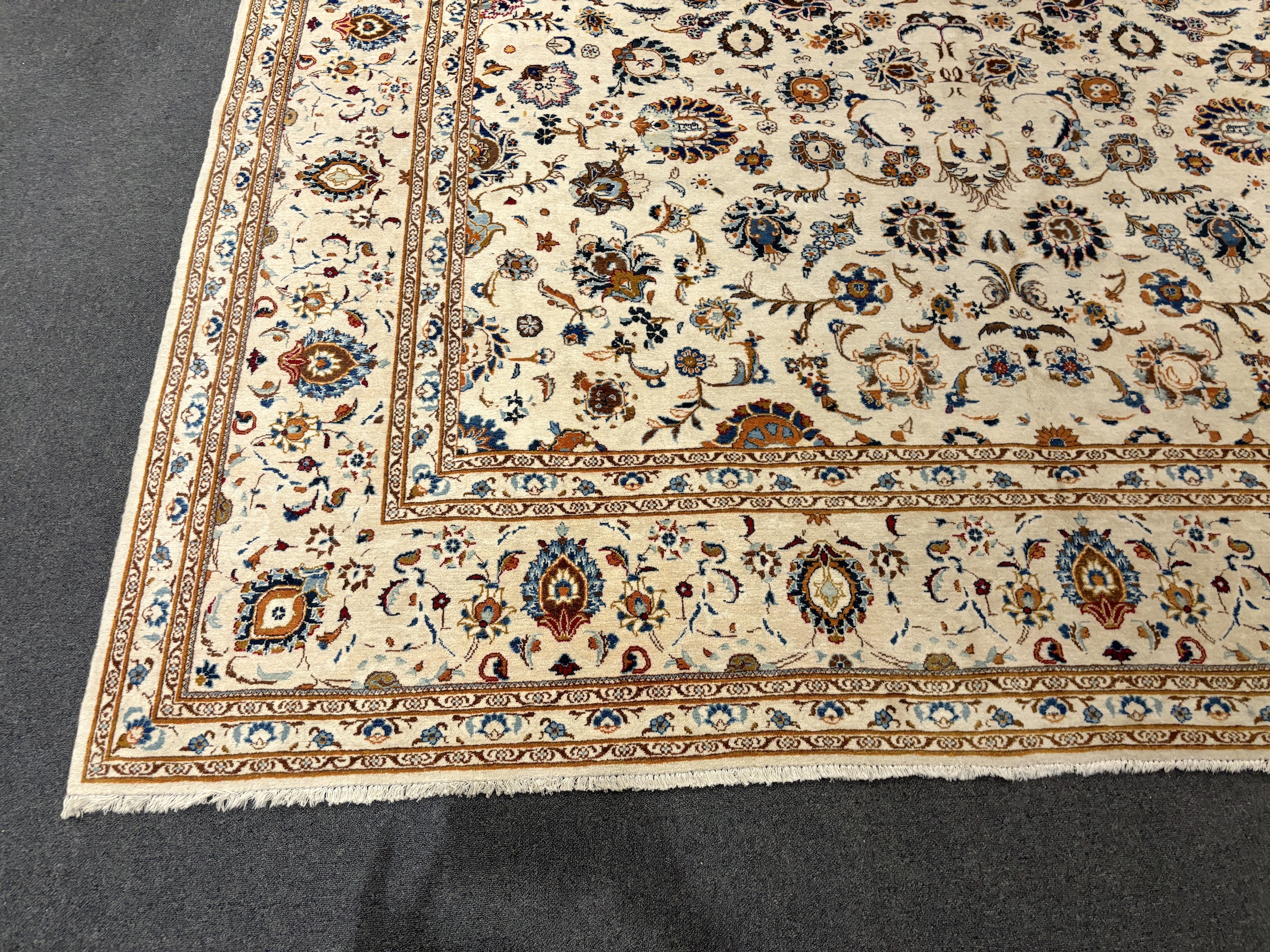 A Kashan ivory ground carpet, central field of foliate motifs, multi bordered, 400 x 308cm, Please note this lot attracts an additional import tax of 5% on the hammer price